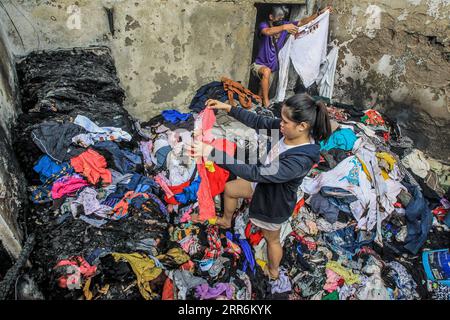 210221 -- MANILA, 21. Februar 2021 -- Bewohner suchen nach intakter Kleidung aus ihrem verkohlten Laden nach einem Brand in einem Slum-Gebiet in Manila, Philippinen am 21. Februar 2021. Fünf Menschen starben, als ein sechsstündiger Brand rund 300 Häuser im Tondo-Viertel von Manila auf den Philippinen zerstörte, sagte ein Feuerwehrmann am Sonntag. PHILIPPINEN-MANILA-FIRE RouellexUmali PUBLICATIONxNOTxINxCHN Stockfoto