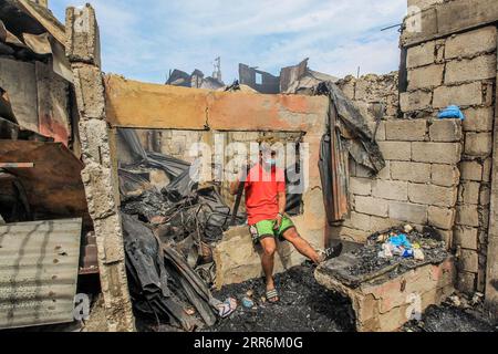 210221 -- MANILA, 21. Februar 2021 -- Ein Bewohner ruht bei der Suche nach Gegenständen aus seinem verbrannten Haus nach einem Brand in einem Slum-Gebiet in Manila, Philippinen, am 21. Februar 2021. Fünf Menschen starben, als ein sechsstündiger Brand rund 300 Häuser im Tondo-Viertel von Manila auf den Philippinen zerstörte, sagte ein Feuerwehrmann am Sonntag. PHILIPPINEN-MANILA-FIRE RouellexUmali PUBLICATIONxNOTxINxCHN Stockfoto