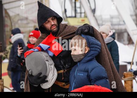 210223 -- MOSKAU, 23. Februar 2021 -- Ein Mitglied eines Reenactment-Clubs hilft einem Jungen, seinen Schutzhelm vor einem Turnierturnier zu tragen, um am 23. Februar 2021 in einem Freizeitpark am Stadtrand von Moskau, Russland, den Tag des Verteidigers des Vaterlandes zu feiern. Der Tag des Verteidigers des Vaterlandes ist ein russischer Nationalfeiertag am 23. Februar, an dem diejenigen geehrt werden, die in den Streitkräften dienen. Foto von /Xinhua RUSSIA-MOSCOW-THE DEFENDER OF THE VATERLAND DAY-FESTLICHE VERANSTALTUNG MaximxChernavsky PUBLICATIONxNOTxINxCHN Stockfoto