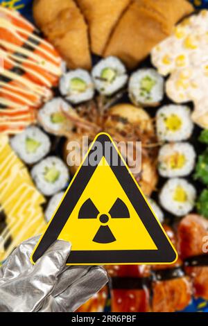 Warnschild für nukleare Strahlung über verschwommener Sushi-Vertikalzusammensetzung Stockfoto