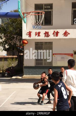 210226 -- LIANGSHAN, 26. Februar 2021 -- Jijue Jizhu 1st L spielt Basketball auf dem Spielplatz mit seinen Freunden in der Schule in der südwestchinesischen Provinz Sichuan, 24. Februar 2021. An einem verschneiten Tag im Februar 2018 ging ein neunjähriger Junge mit seinem jüngeren Bruder auf dem Rücken in der Autonomen Präfektur Liangshan Yi in der Provinz Sichuan bergab, auf dem Weg zum Haus seines Großvaters mütterlicherseits an einem Umzugsort. Xinhua-Korrespondent hat den Moment festgehalten. Das Foto bewegte viele Chinesen. Mit Hilfe gezielter Armutsbekämpfung verabschiedete sich Jijue Jizhus Familie von dem lehmhaus in einem Berggebiet Stockfoto