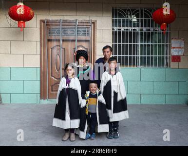 210226 -- LIANGSHAN, 26. Februar 2021 -- Jijue Jizhu 1st R posiert für ein Gruppenfoto mit seinen Familienmitgliedern im Hof ihres neuen Hauses in der südwestchinesischen Provinz Sichuan, 24. Februar 2021. An einem verschneiten Tag im Februar 2018 ging ein neunjähriger Junge mit seinem jüngeren Bruder auf dem Rücken in der Autonomen Präfektur Liangshan Yi in der Provinz Sichuan bergab, auf dem Weg zum Haus seines Großvaters mütterlicherseits an einem Umzugsort. Xinhua-Korrespondent hat den Moment festgehalten. Das Foto bewegte viele Chinesen. Mit Hilfe gezielter Armutsbekämpfung verabschiedete sich Jijue Jizhus Familie vom lehmhaus Stockfoto