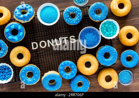 Mehrere verzierte und einfache Donuts mit dem Wort Donuts in der Mitte. Stockfoto