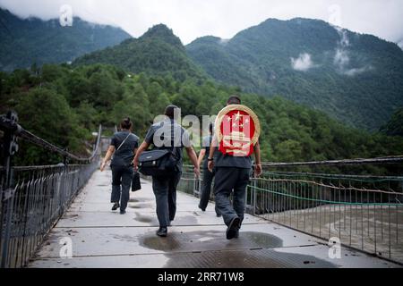 210308 -- PEKING, 8. März 2021 -- Deng Xing, Richter am Volksgericht des Gongshan County, trägt das nationale Emblem auf seinem Rücken, während er mit seinen Kollegen auf einer Brücke über den Fluss Nujiang auf ihrem Weg zur Arbeit in der Autonomen Präfektur Nujiang Lisu, Provinz Yunnan im Südwesten Chinas, am 30. August 2019, spaziert. Xinhua-Schlagzeilen: Ein Blick auf Chinas Demokratie, Rechtsstaatlichkeit auf zwei Sitzungen JiangxWenyao PUBLICATIONxNOTxINxCHN Stockfoto