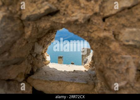 Blick auf den Gardasee durch ein Loch in der Stadtmauer im Ferienort Limone Sul Garda in Italien Stockfoto