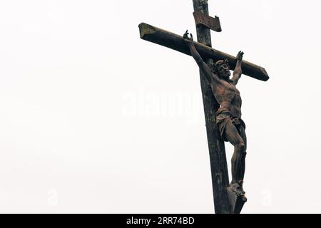 Statue der gekreuzigten christus am Kreuz eines Tempels auf einem Friedhof an einem bewölkten Tag im Freien Stockfoto