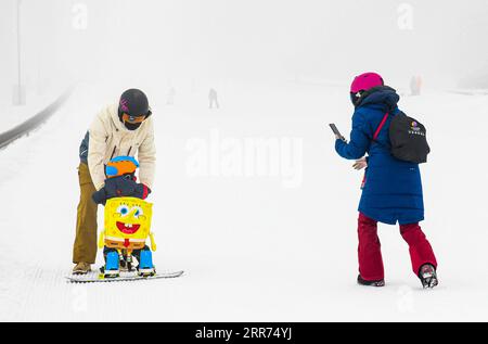 210312 -- ÜRÜMQI, 12. März 2021 -- Foto aufgenommen am 4. März 2021 zeigt, wie der Snowboardtrainer Xu Xiujuan R Fotos für ihren Mann und Sohn im Baiyun Ski Resort in Ürümqi, der nordwestlichen chinesischen Autonomen Region Xinjiang Uygur, macht. Der 31-jährige Xu Xiujuan ist heute technischer Direktor und Mitglied des rates der Xinjiang Skiverband. Im Alter von 9 Jahren begann sie in ihrer Heimatstadt Harbin, der Hauptstadt der nordöstlichen chinesischen Provinz Heilongjiang, Skifahren zu lernen. Während ihrer Karriere als Athletin erzielte Xu im Auftrag Chinas große Erfolge bei nationalen und internationalen Wintersportveranstaltungen Stockfoto