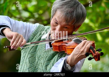 210320 -- FUZHOU, 20. März 2021 -- Ein Bürger spielt Geige im Jinshan Park in Fuzhou, Provinz Fujian im Südosten Chinas, 10. März 2021. Umgeben von Hügeln und Bergen auf drei Seiten ist die Küstenstadt Fuzhou die Hauptstadt der Provinz Fujian im Südosten Chinas. Die Hauptstadt mit ihrem reichen kulturellen und historischen Erbe ist mit ihrem Spitznamen beliebter: Banyan City, da in der ganzen Stadt zahlreiche Banyan-Bäume gepflanzt werden, die den Bürgern entlang von Straßen und Straßen Schatten bieten. Der Fluss Minjiang fließt durch die Stadt und Fuzhou genießt ein günstiges Klima und hohe Niederschläge, was Fuz ausmacht Stockfoto