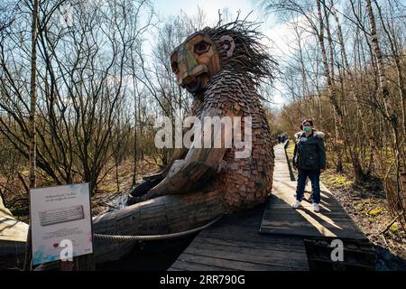 210321 -- BOOM, 21. März 2021 -- Menschen sehen einen Troll im de Schorre Forest Park in Boom, Belgien, 20. März 2021. Der dänische Künstler Thomas Dambo und sein Team bauten 2019 im Waldpark de Schorre im Norden Belgiens sieben riesige Trolle aus wiedergewonnenem Holz. Diese riesigen Holzskulpturen sind um den Wald gestreut. Die Generalversammlung der Vereinten Nationen hat den 21. März zum Internationalen Tag der Wälder ausgerufen, an dem die Bedeutung aller Arten von Wäldern und die Notwendigkeit, die Wälder der Welt zu erhalten und zu pflegen, gefeiert und das Bewusstsein dafür geschaffen wird. Dieses Jahr das Thema für die Internationale Stockfoto