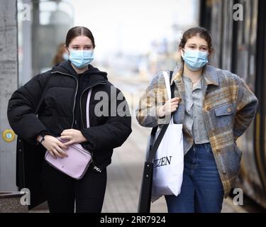 210320 -- WARSCHAU, 20. März 2021 -- Menschen mit Gesichtsmasken gehen am 20. März 2021 neben einer Straßenbahn im Zentrum von Warschau, Polen. Die polnische Regierung kündigte am Freitag eine neue landesweite Teilsperrung an, nachdem die kumulative Zahl der COVID-19-Fälle seit Beginn der Pandemie zwei Millionen im Land überschritten hatte. Ab Samstag darf nur eine ausgewählte Anzahl von Geschäften - darunter Supermärkte und Apotheken - in Einkaufszentren mit über 2.000 Quadratmetern Verkaufsfläche betrieben werden. Kinos, Theater und Museen müssen geschlossen bleiben, und die Schulen werden wieder zu o zurückkehren Stockfoto