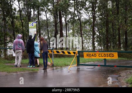 210322 -- SYDNEY, 22. März 2021 -- Leute überprüfen Informationen neben einer gesperrten Straße in Penrith, Sydney, Australien, 22. März 2021. Starke Regenfälle verursachten am Sonntag weiterhin gefährliche Überschwemmungen im australischen Bundesstaat New South Wales NSW, was von den Behörden als ein-in-50-jährliches Ereignis bezeichnet wurde. AUSTRALIEN-SYDNEY-STARKE REGENFLUT BaixXuefei PUBLICATIONxNOTxINxCHN Stockfoto