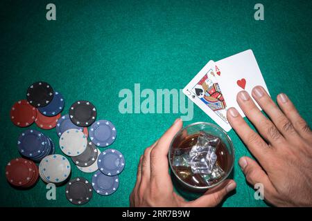 Pokerspieler zeigt Jack-Ass-Karte mit Casino-Chips grünem Pokertisch Stockfoto