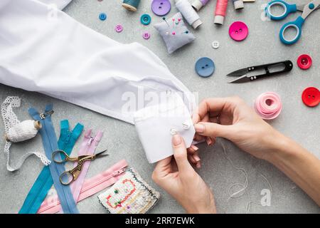 Frauenhände nähen weißes Hemd oben Stockfoto