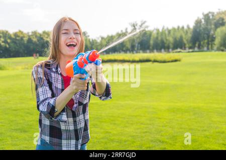 Ein fröhliches Mädchen mit mittlerer Schussweite, das mit einer Wasserpistole spielt Stockfoto