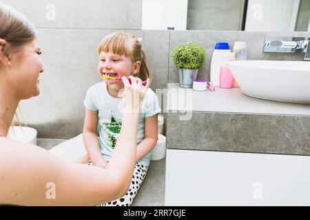 Mutter, die Zähne putzt, Tochter Stockfoto