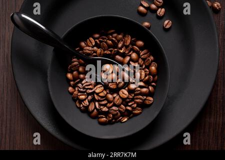 Schüssel mit gerösteten Kaffeebohnen und Löffel Stockfoto
