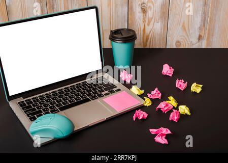 Türkisfarbene Maus Haftnotiz Take Away Tasse zerknitterte Papier Laptop mit weißem Bildschirm Display schwarzer Hintergrund Stockfoto