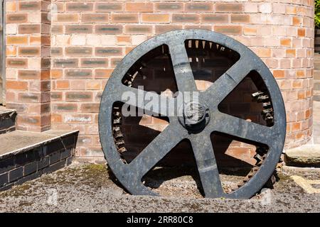 Riesiges, rostendes, verlassenes Schwungrad aus einer viktorianischen Ära mit Hubmotor und alten Eisenwerken Stockfoto