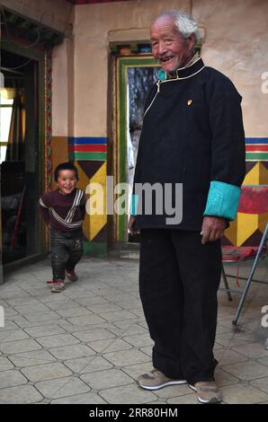 210410 -- LHASA, 10. April 2021 -- Dawa Gokye lächelt, als sein Enkel in ihrer Residenz im Gyadu Village of Jangra Township im Gyangze County of Xigaze City spielt, im Südwesten Chinas autonome Region Tibet, 22. März 2021. Dawa Gokye, 76, einst Leibeigene in einem lokalen Herrenhaus Tibets, hatte bis zur demokratischen Reform 1959 in Hoffnungslosigkeit und Verzweiflung gelebt. In den Augen der Sklavenhalter sind Sklaven nichts anderes als sprechende Werkzeuge, die ihnen ausgeliefert sind. Dawa erinnerte sich, dass sein Kopf vom Verwalter des Herrenhauses schwer verletzt wurde, da der damals 8-Jährige das Wasser nicht heiß genug kochte, um Tee zu machen. Zusammen mit Dutzenden von denen Stockfoto