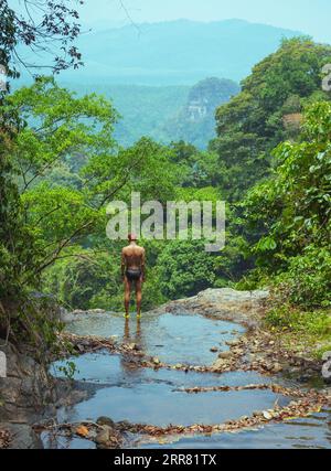 Das Konzept der Einheit mit Natur und Gesundheit. Südostasiatischer (Thai) Mann in Badehose steht am Rande des Wasserfalls im Khao Phanom Bencha Nationalpark Stockfoto