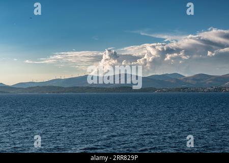 Meereslandschaft mit Windturbinen auf den Bergen entlang der Küste im Hintergrund. Stockfoto