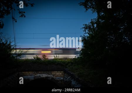 Passenger train on railroad tracks at night Stockfoto