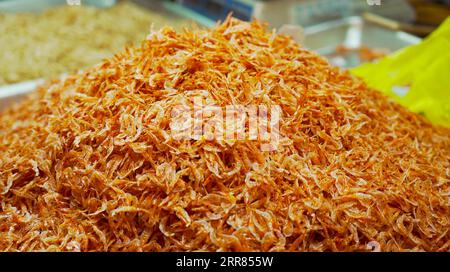 Ein Haufen getrockneter Garnelen im Überfluss. Im Inneren des Shops sind die Regale bis zum Rand mit Shrimps gefüllt, die ein Meer von Meeresfrüchten erzeugen Stockfoto