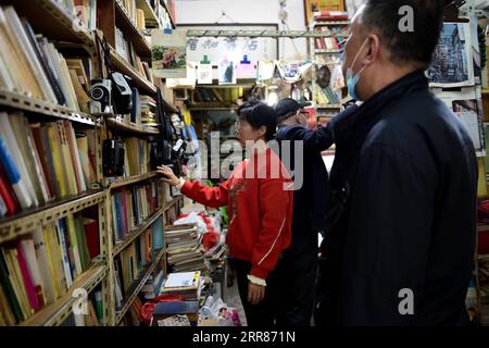 210422 -- HEFEI, 22. April 2021 -- Chen Guixia 1st L wählt Bücher für einen Kunden im Zengzhi Bookshop in Hefei, ostchinesische Provinz Anhui, 19. April 2021. Seit seiner Eröffnung vor 21 Jahren gilt der Zengzhi Bookshop, ein unscheinbarer Second-Hand-Buchhändler in der Innenstadt von Hefei, als intellektuelles Wahrzeichen unter lokalen Buchfans. Sein verstorbener Besitzer Zhu Chuanguo rühmte sich mit einer Sammlung von 000 gebrauchten Büchern, die alle von normalen Lesern und Recyclingunternehmen gekauft wurden. Unter Zhus Vision können sich die ausgefallenen Bücher als aufschlussreich für jemand anderen erweisen, der daher eine r verdient Stockfoto