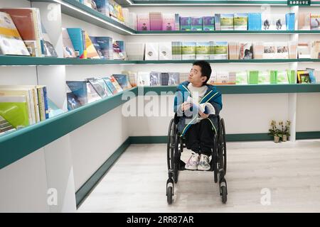 210423 -- PEKING, 23. April 2021 -- Liu Daming, ein Osteogenesis imperfecta-Patient und Buchautor, besucht die Shanyuan-Bücherkammer in Peking, Hauptstadt Chinas, 14. April 2021. In der Shanyuan Book Chamber, einem barrierefreien Buchladen, werden bei jedem Design und Layout die Bedürfnisse behinderter Leser berücksichtigt. Auf einer Fläche von über 300 Quadratmetern im Bezirk Dongcheng, Peking, bietet der Buchladen Bücherregale mit alternativen Höhen, abgerundete Möbel, ausreichend Platz für Rollstühle und andere Einrichtungen, um die Zugänglichkeit zu verbessern. Darüber hinaus legt die Buchhandlung viel Wert auf Stockfoto