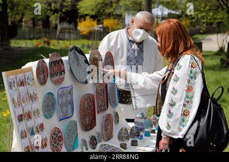 210425 -- BUKAREST, 25. April 2021 -- ein Handwerker präsentiert seine Waren einem Kunden während einer traditionellen Frühlingsmesse, die im rumänischen Dorfmuseum in Bukarest, Rumänien, am 24. April 2021 organisiert wird. Handwerker aus dem ganzen Land kamen im Dorfmuseum an, um ihre Handwerkskunst zu beweisen und ihre Waren zu verkaufen. Foto von /Xinhua ROMANIA-BUKAREST-HANDWERKSMESSE CristianxCristel PUBLICATIONxNOTxINxCHN Stockfoto