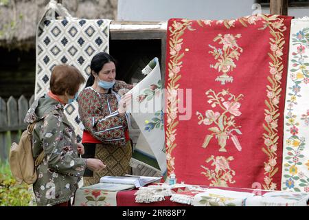 210425 -- BUKAREST, 25. April 2021 -- eine Kunsthandwerkerin präsentiert ihre Waren einem Kunden während einer traditionellen Frühlingsmesse, die im rumänischen Dorfmuseum in Bukarest, Rumänien, am 24. April 2021 organisiert wird. Handwerker aus dem ganzen Land kamen im Dorfmuseum an, um ihre Handwerkskunst zu beweisen und ihre Waren zu verkaufen. Foto von /Xinhua ROMANIA-BUKAREST-HANDWERKSMESSE CristianxCristel PUBLICATIONxNOTxINxCHN Stockfoto