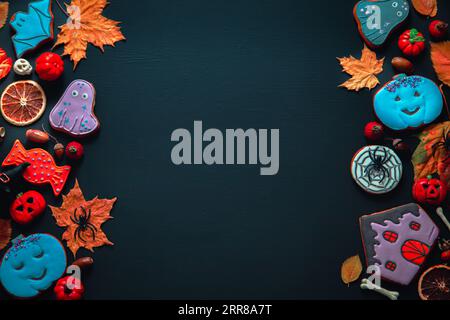 Halloween Herbsthintergrund. Bemalte Lebkuchen, Kürbisse und Blätter auf schwarzem Hintergrund. Stockfoto