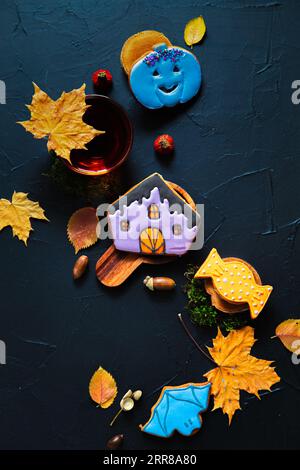Herbsttee. Tasse Tee, bemalte Lebkuchen, Eicheln und Blätter auf schwarzem Hintergrund. Stockfoto