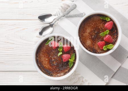 Schokoladencreme-Brulee-Dessert, bestehend aus einer reichhaltigen Puddingbasis, gekrönt von einer Schicht gehärtetem karamelisierten Zucker aus der Nähe in einem Ramekin auf dem Tisch. Stockfoto