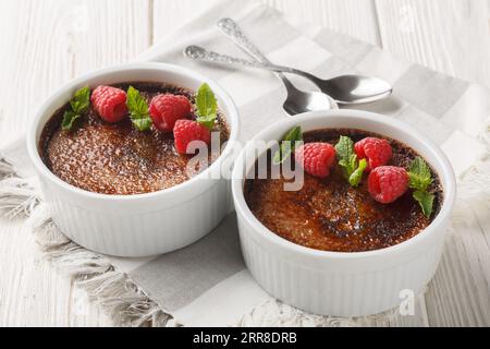 Schokoladencreme-Brulee-Dessert, bestehend aus einer reichhaltigen Puddingbasis, gekrönt von einer Schicht gehärtetem karamelisierten Zucker aus der Nähe in einem Ramekin auf dem Tisch. Stockfoto