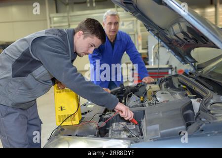 Schüler mit Lehrer, die Reparatur eines Autos während der Lehrzeit Stockfoto