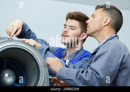 flugingenieur und Auszubildender, die im Hangar am Flugzeug arbeiten Stockfoto