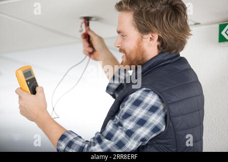 Elektriker die Messung der Spannung der Kabel an der Decke im Innenbereich Stockfoto