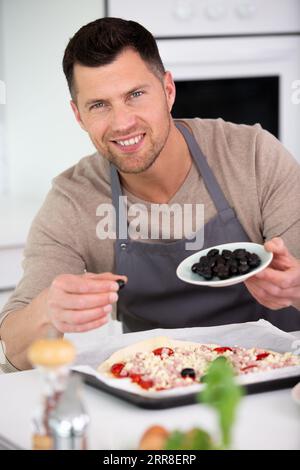 Mann, der hausgemachte Pizza in einer heimischen Küche kocht Stockfoto