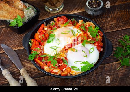 Shakshuka mit gegrilltem Brot. Spiegeleier mit Tomaten, Pfeffer, Knoblauch und Kräutern Stockfoto