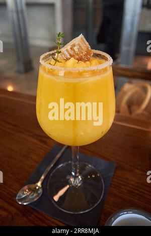 Cooler Mango Smoothie mit Wabenauflage Stockfoto