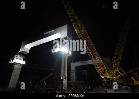 210514 -- LANZHOU, 14. Mai 2021 -- Workers of the Road and Bridge Engineering Co., Ltd. der China Railway Seventh Group arbeiten am frühen Morgen des 14. Mai 2021 auf einer Baustelle, um Stahlträger einer Brücke entlang der Zhongwei-Lanzhou Personenbahnlinie in Lanzhou, der nordwestchinesischen Provinz Gansu, zu platzieren. Nach zwei aufeinanderfolgenden Nachtsitzungen gelang es den Arbeitern, am Freitagmorgen Stahlträger der Brücke über eine bestehende Eisenbahn zu platzieren. Die Brücke ist ein Schlüsselprojekt für die 173 Kilometer lange Personenbahnstrecke, die Lanzhou und Zhongwei mit dem benachbarten Ningxia Hui Autonomou verbindet Stockfoto