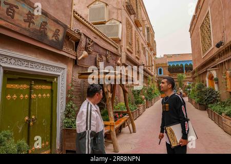 210514 -- KASHGAR, 14. Mai 2021 -- Mamattursunjian Mamatimen R bereitet sich auf das Malen in einer Gasse in der antiken Stadt Kashgar in der nordwestchinesischen autonomen Region Xinjiang Uygur vor, 6. Mai 2021. Die dominierende Farbe der Wohnungen in der antiken Stadt Kashgar in Xinjiang ist tiefgelb. Aber in den Werken des 26-jährigen lokalen Malers Mamattursunjian Mamatimen, mehr Farben wie Orange, weiß, lila, blau... Werden verwendet, um die Stadt zu malen. Das ist sein Lebensgefühl, und auch ein Gefühl, das von den Jugendlichen in Kashgar geteilt wird, sagte Mamattursunjian. Es braucht Mut, die Tradition zu durchbrechen. Mamattursunjian s Stockfoto