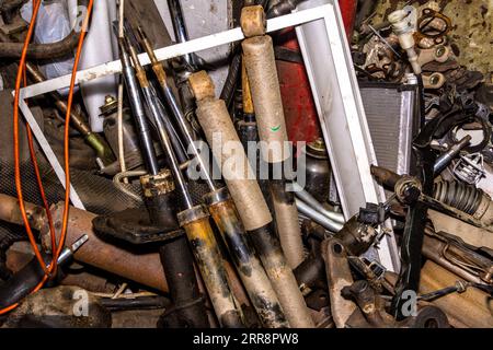 In der Ecke der Servicestation ein Haufen alter Ersatzteile nach der Reparatur der Fahrzeugaufhängung - Stoßdämpfer mit Stabilisator und Verwendung Stockfoto