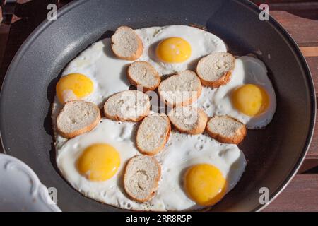 Frisch gekochte Spiegeleier in einer Pfanne, selektiver Fokus. Essen im Freien bei Sonnenlicht Stockfoto