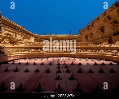 Detaillierter Blick von unten auf die Ornamente auf der roten Haupttür aus Holz mit schmiedeeisernen Motiven und das Gesims mit Wasserspeiern der Neuen Kathedrale von Stockfoto