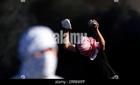 210518 -- NABLUS, 18. Mai 2021 -- Ein Demonstrant hält Steine fest, um israelische Soldaten während eines Protestes gegen die anhaltenden israelischen Luftangriffe auf den Gazastreifen am Huwwara Checkpoint in der Nähe der Westbank-Stadt Nablus am 18. Mai 2021 zu schleudern. Vier Palästinenser wurden am Dienstag getötet und 64 weitere wurden bei Zusammenstößen mit israelischen Soldaten im Westjordanland verletzt, sagten medizinische Quellen. Foto von /Xinhua MIDEAST-NABLUS-CLASHES AymanxNobani PUBLICATIONxNOTxINxCHN Stockfoto