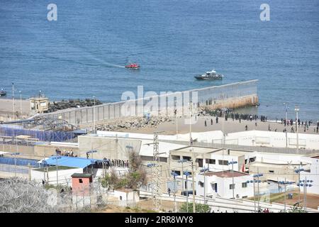 210519 -- FNIDEQ, 19. Mai 2021 -- potenzielle Migranten stehen auf der marokkanischen Seite des Zauns, der die spanische Enklave von Marokko trennt, in Fnideq, Marokko, am 18. Mai 2021. Die spanische Enklave Ceuta muss mit einem Zustrom von Einwanderern fertig werden, nachdem schätzungsweise 6.000 Menschen von Marokko aus in das Gebiet eingedrungen sind, so die Delegation der Zentralregierung in der Stadt. MAROKKO-FNIDEQ-SPANIEN-IMMIGRANTEN Xinhua PUBLICATIONxNOTxINxCHN Stockfoto