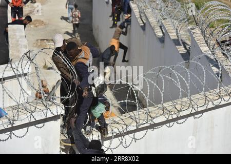 210519 -- FNIDEQ, 19. Mai 2021 -- Immigranten klettern über den Grenzzaun in die spanische Enklave Ceuta in Fnideq, Marokko, 18. Mai 2021. Die spanische Enklave Ceuta muss mit einem Zustrom von Einwanderern fertig werden, nachdem schätzungsweise 6.000 Menschen von Marokko aus in das Gebiet eingedrungen sind, so die Delegation der Zentralregierung in der Stadt. MAROKKO-FNIDEQ-SPANIEN-IMMIGRANTEN Xinhua PUBLICATIONxNOTxINxCHN Stockfoto