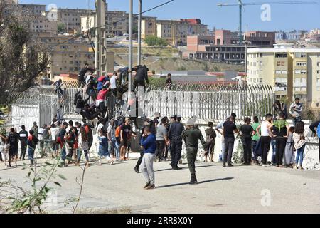 210519 -- FNIDEQ, 19. Mai 2021 -- Immigranten klettern über den Grenzzaun in die spanische Enklave Ceuta in Fnideq, Marokko, 18. Mai 2021. Die spanische Enklave Ceuta muss mit einem Zustrom von Einwanderern fertig werden, nachdem schätzungsweise 6.000 Menschen von Marokko aus in das Gebiet eingedrungen sind, so die Delegation der Zentralregierung in der Stadt. MAROKKO-FNIDEQ-SPANIEN-IMMIGRANTEN Xinhua PUBLICATIONxNOTxINxCHN Stockfoto